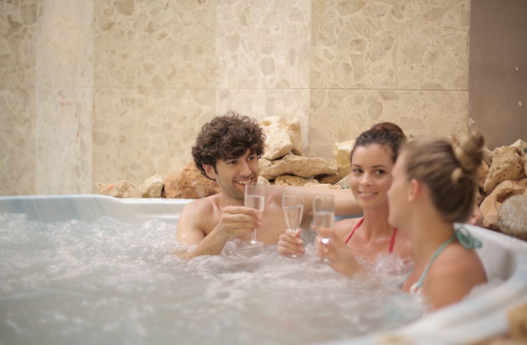 Group of friends smiling and clinking glasses while relaxing in a bubbling indoor spa